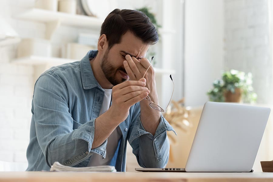 Young man rubbing his eyes because of blurry vision related to neurological issues.