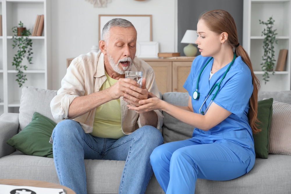 nurse assisting elderly man with Parkinson’s during deep brain stimulation recovery, offering supportive care at home