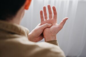 person pressing palm to relieve hand tremor possibly linked to Parkinson’s, related to deep brain stimulation therapy