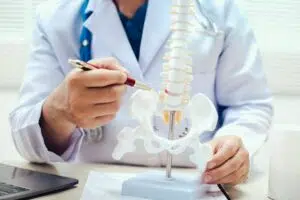 Medical professional using spine model to explain surgical procedures for spinal conditions and nerve-related issues.