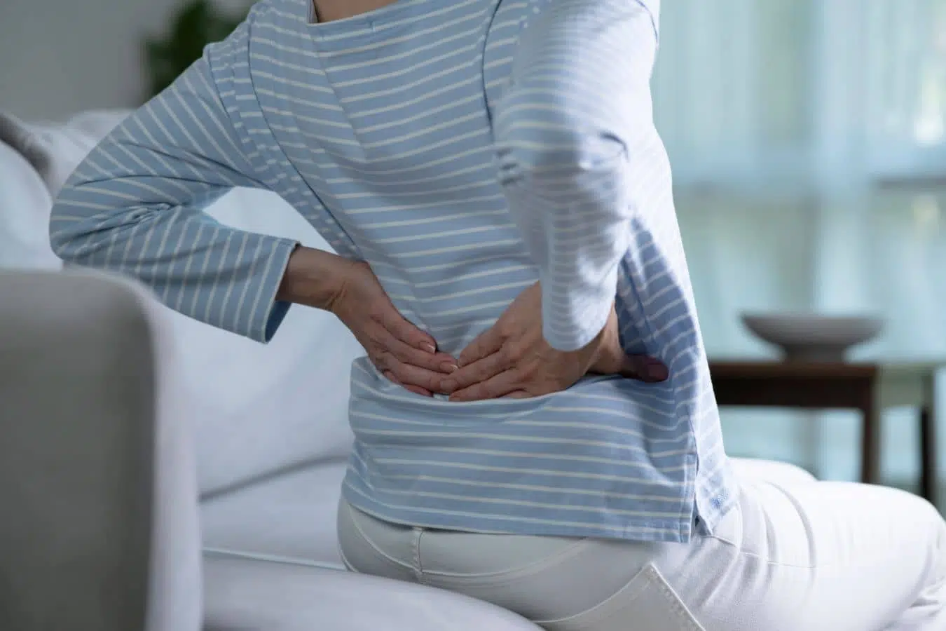 Person sitting and holding lower back, illustrating chronic axial low back pain linked to Modic changes without leg symptoms