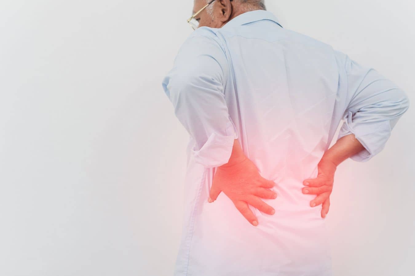 Older adult holding lower back in pain, highlighting chronic mechanical low back pain linked to multifidus dysfunction